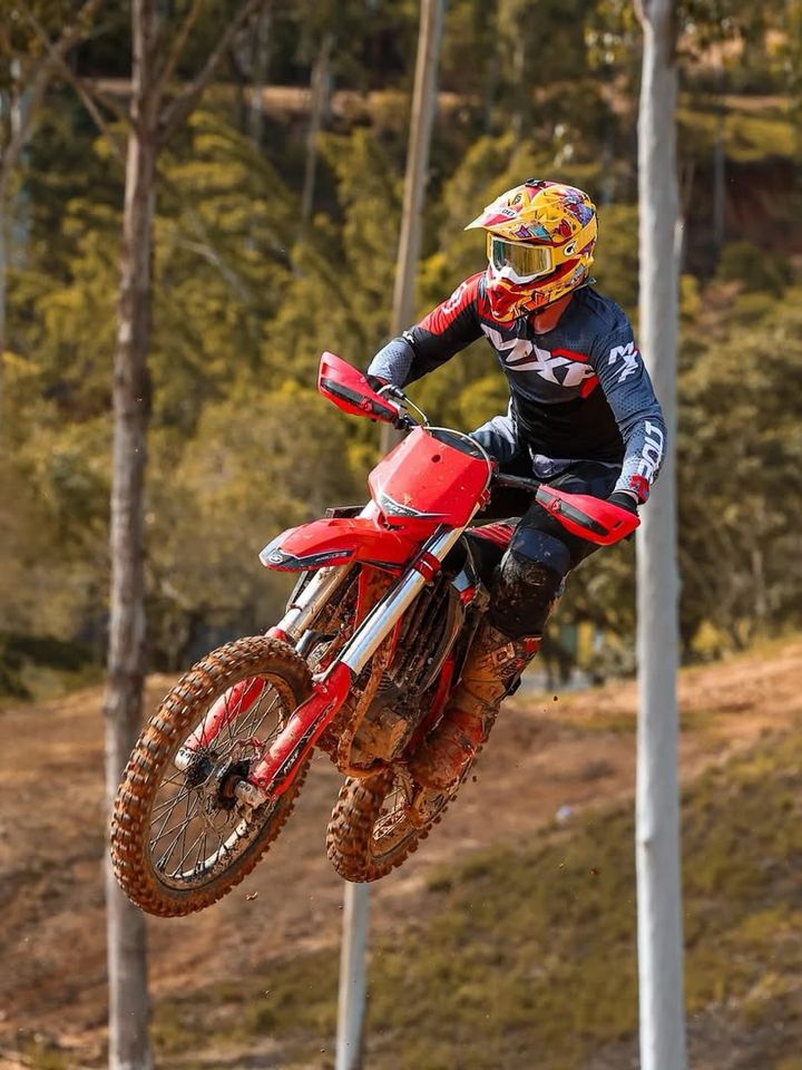 Piloto saltando com uma moto MXF em pista de terra